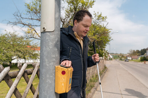 Mann mit Behinderung steht an einer Ampel 