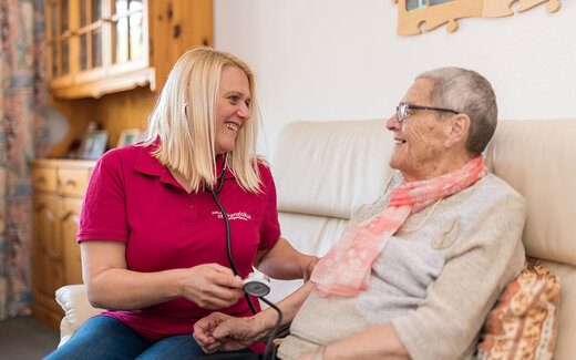 Pflegerin misst bei Seniorin den Blutdruck 