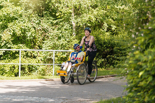 Betreuerin geht mit Jungen mit Behinderung Fahrrad fahren 